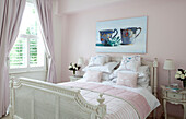 Kunstwerk aus Porzellan über einem weiß gestrichenen Doppelbett in einem pastellrosa Schlafzimmer in einem modernen Haus in London, Vereinigtes Königreich