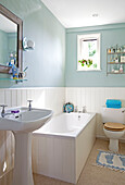 Pastel green bathroom with white panelling in Sussex cottage, England, UK