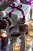 Gift-wrapped present and baubles in Surrey farmhouse with tealights, England, UK