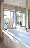 White bath in Surrey farmhouse with orchid at window, England, UK