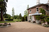 Gravel driveway and with water fountain and lawned exterior of Sussex country house, England, UK