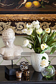 Antique bust and tealights with cut tulips in Sussex country house, England, UK