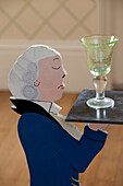 Single wineglass on novelty side table in shape of a waiter, Sussex country house, England, UK