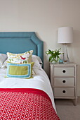 Red blanket on bed with blue headboard in London townhouse, England, UK
