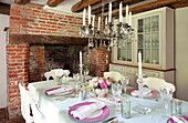Dining table with glass chandelier and exposed brick fireplace in Maidstone farmhouse, Kent, England, UK