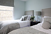 Abgestimmtes Zweibettzimmer mit grauen Möbeln in einem modernen Londoner Stadthaus, England, UK