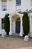 Nadelbäume auf beiden Seiten der Veranda eines Landhauses in Sussex England UK