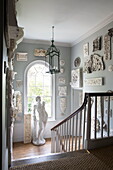 Historic plasterwork and male statue in arched window of staircase in Sussex country home England UK