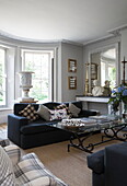 Dark grey sofa with glass topped coffee table in historic Sussex country home England UK