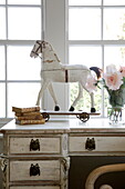 Toy horse and books on dressing table at bedroom window of historic Sussex country home England UK