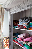 Gefaltete Pullover auf einem Regal im Schlafzimmer eines Hauses in Sussex, England, UK