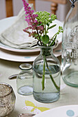 Cut flowers in vintage bottle on kitchen table in Sussex Downs home England UK