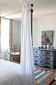 Blue painted chest of drawers with white fabric on four poster bed in Mougins bedroom, Alpes-Maritime, South of France