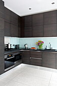 Dark wood fitted kitchen in contemporary London townhouse, England, UK