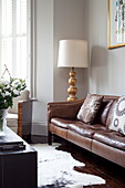 Standard lamp and animal skin rug with brown leather sofa in London townhouse, England, UK