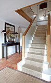 Carpeted staircase and console in terracotta tiled hallway of Kent home, England, UK