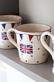 Union Jack mugs on kitchen shelf in Staffordshire farmhouse England UK