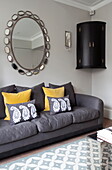 Large vintage mirror and corner cabinet with grey sofa in London townhouse England UK