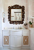 Ornate mirror in recessed wash basin sink unit in Kent family home England UK
