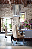 Large metallic pendant light above dining table and chairs in French holiday villa