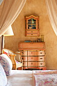 Peach painted furniture in bedroom of French holiday villa