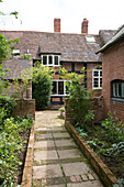 Paved path with archway at brick exterior of Herefordshire home, England, uk