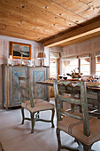 Dining table and side cabinet below wooden ceiling in mountain chalet in Chateau-d'Oex, Vaud, Switzerland