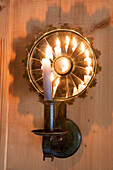 Lit candle wall sconce with flame reflected in mountain chalet in Chateau-d'Oex, Vaud, Switzerland