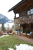 Klappstühle und Tisch unter dem Balkon eines Bergchalets in Chateau-d'Oex, Waadt, Schweiz