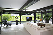 White sofa, black recliner and bonsai with view to garden in contemporary SW London home, England, UK
