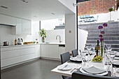 Open plan basement kitchen with laid table in contemporary Brighton home, East Sussex, England, UK