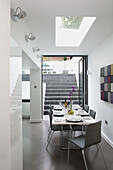 Grey dining chairs at table with modern artwork in contemporary Brighton home, East Sussex, England, UK