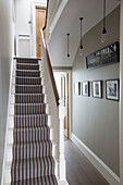Gestreifter Teppich und Kunstwerke im Treppenhaus eines modernen Hauses in Brighton, East Sussex, England, UK