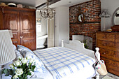 Karierte Decke auf einem Bett mit offenem Kamin in einem Schlafzimmer in West Sussex, England UK