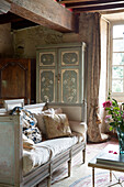 Vintage day bed with painted cupboard unit in living room of French farmhouse in the Loire, France, Europe