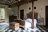 Antique wicker bed between wooden pillars in spacious bedroom of country house in the Loire France Europe