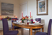 Purple dining chairs at dining table with lit candles in West Sussex home, England, UK