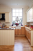 Cream tongue and groove kitchen with wooden laminate floor in West Sussex home, England, UK