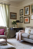 Beistelltisch aus Holz und Sofa mit gerahmten Kunstwerken im Wohnzimmer eines Hauses in London England UK