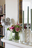 Cut flowers and glass candlesticks on mantlepiece in London home England UK