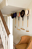 Hats and croquet mallets above armchair in hallway of London home England UK