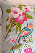 Embroidered floral design with parrot on cushion in London home England UK