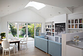 Open plan dining room with blue leather sofas and bookcase in London townhouse, England, UK