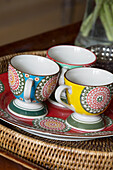 Three patterned cups on a plate in a basket, London home, England, UK