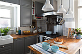 Blue bowls on wooden workbench in grey fitted kitchen of London home, England, UK