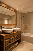 Cream bathroom with large wooden mirror frame and wash stand in London home, England, UK