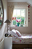 Sunlight falls onto pillows with floral patterned duvet in girl's bedroom, London home, England, UK