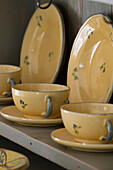 Yellow cups and saucers with plates on kitchen dresser of UK farmhouseUK