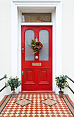 Christmas garland on bright red front door of London home, England, UK