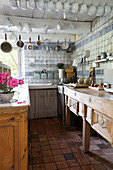 Carved wooden workbench with chinaware in tiled French farmhouse kitchen